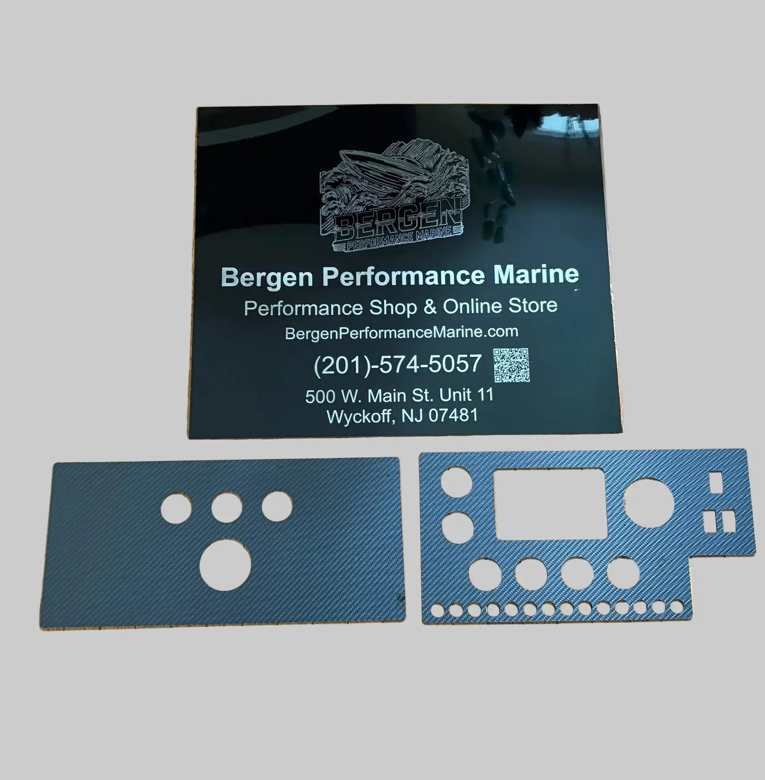 Black glossy business card for bergen performance marine with white engraved text and logo, accompanied by two blue carbon fiber dashboard panel inserts.